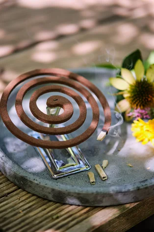 Illustration - Ihr Experte für schönes Wohnen - Brennende Moskitospirale mit Citronella auf einem Holztisch im Freien im Sommer